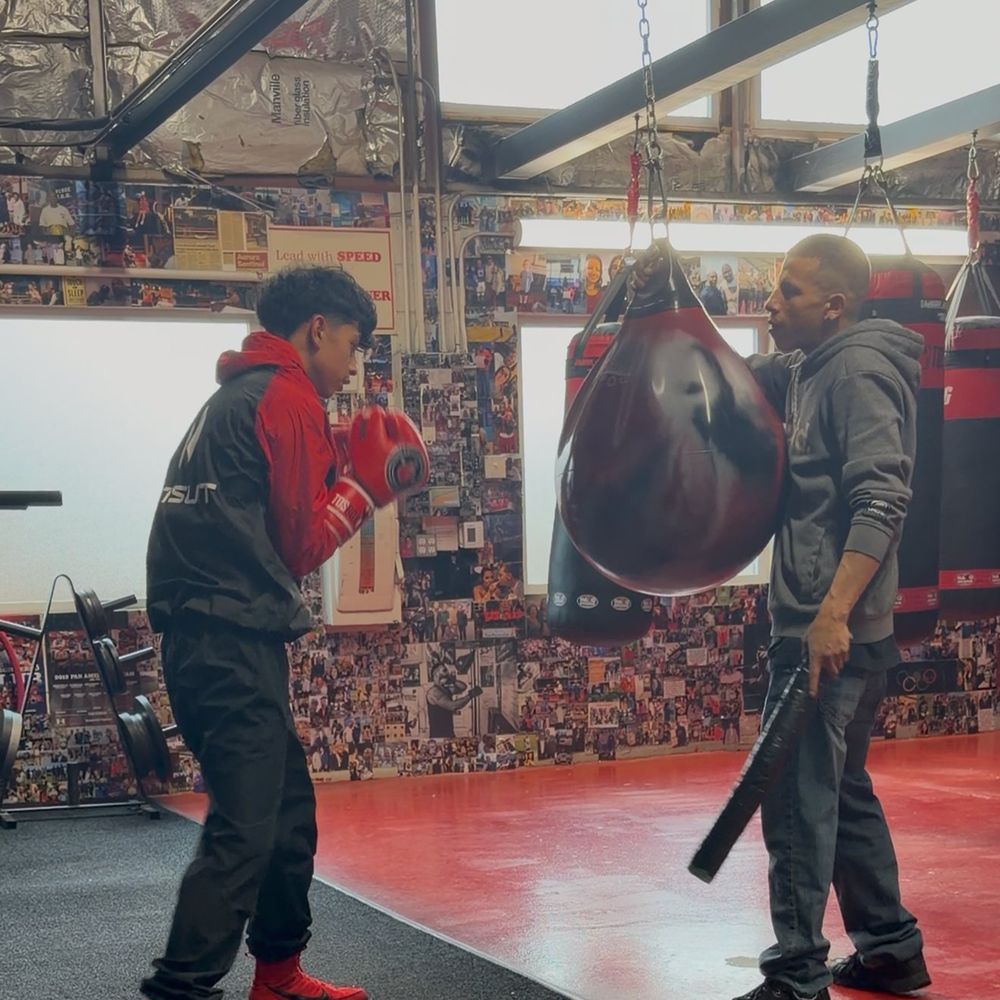 A young boxer working the bag with a coach
