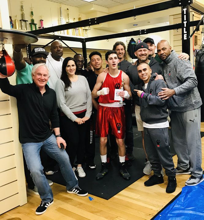 TOS boxer with trophy and USA Boxing passbook after a win